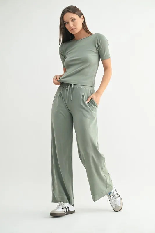 Woman wearing a green loungewear set with wide-leg pants on a white background