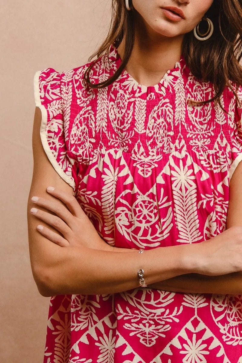 Person wearing a pink and white patterned dress with arms crossed against a beige background
