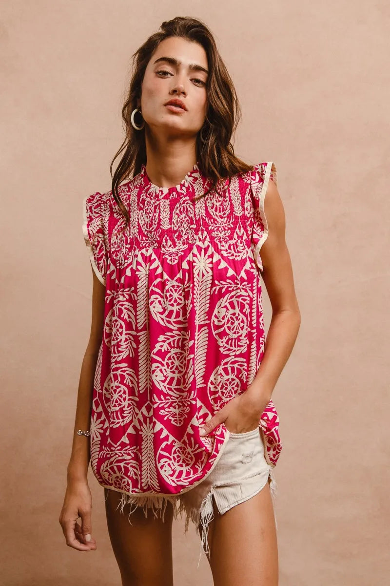Woman wearing a pink and white patterned sleeveless top with white shorts against a beige background