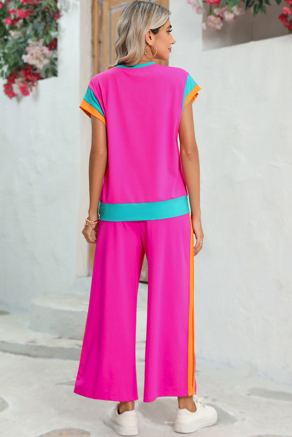Woman wearing a colorful outfit with a pink top and pants against a white background