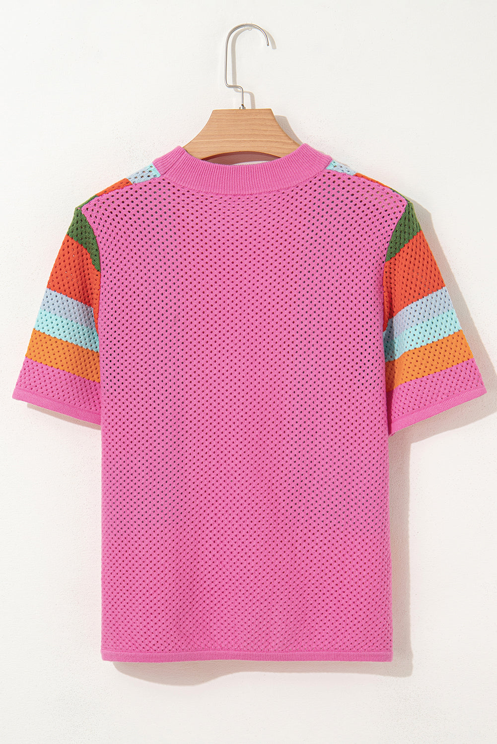 Pink textured t-shirt with colorful sleeves on a hanger against a white background