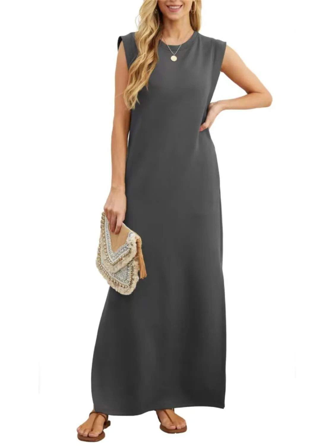 Woman wearing a gray sleeveless dress holding a beige clutch on a white background