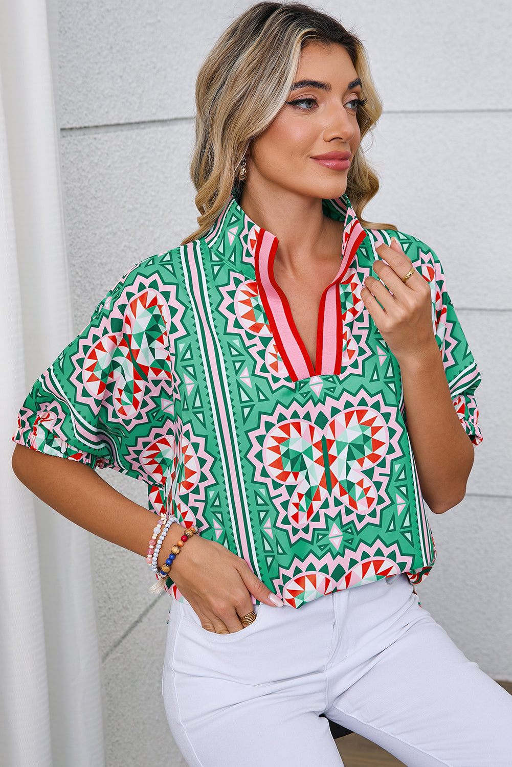 Woman wearing a colorful patterned blouse with a plain background