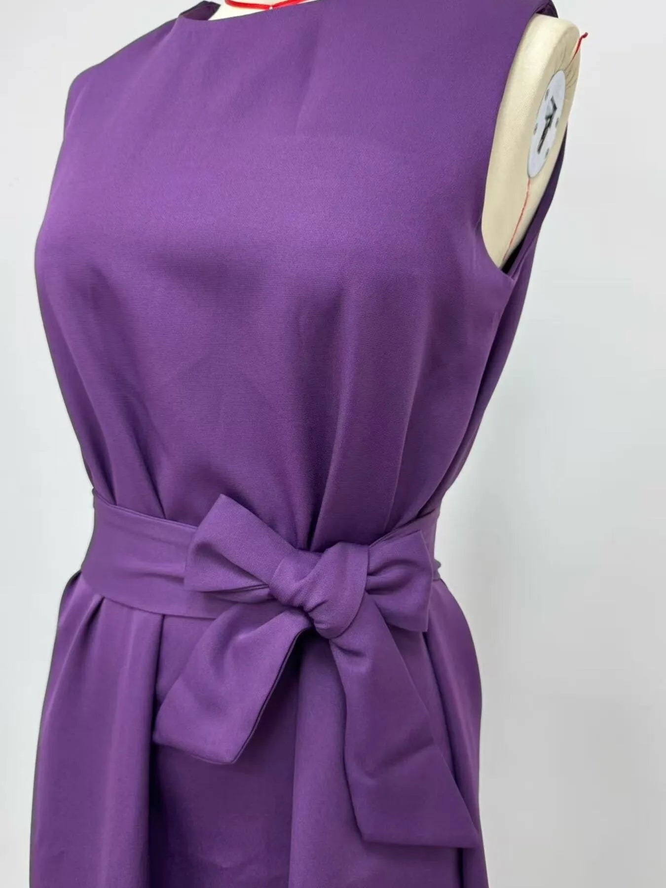 Purple dress with a bow on a mannequin against a white background