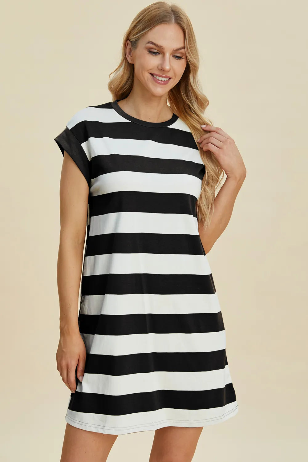 Woman wearing a black and white striped dress on a beige background