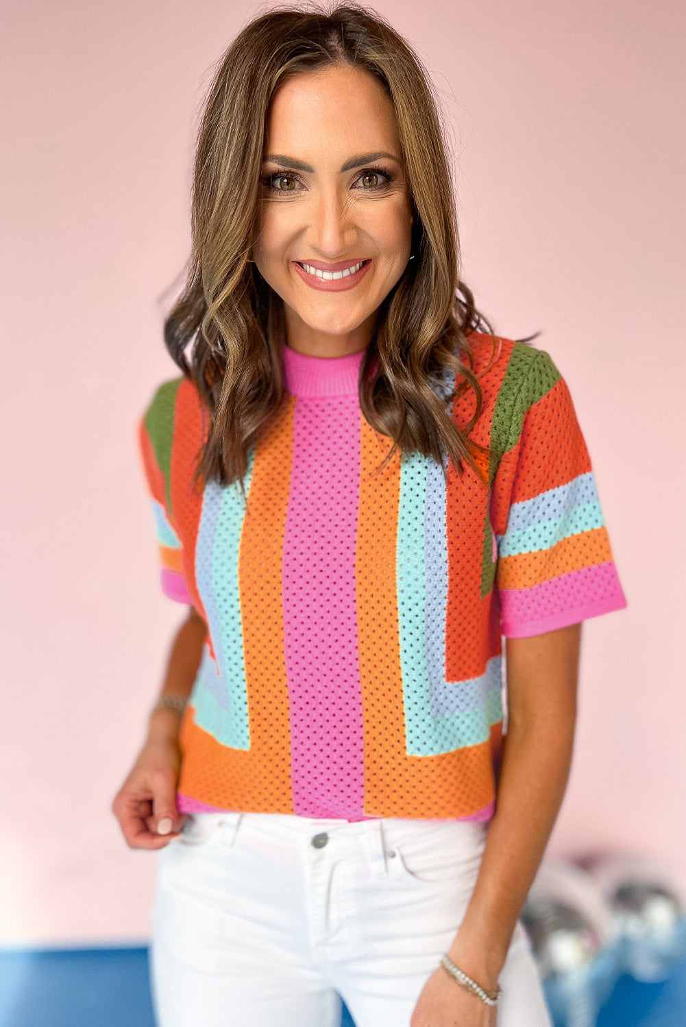 Woman wearing a colorful striped shirt with a pink background
