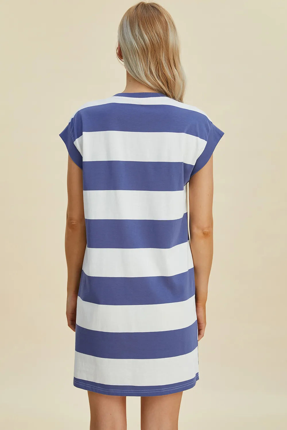 Woman wearing a blue and white striped dress against a beige background