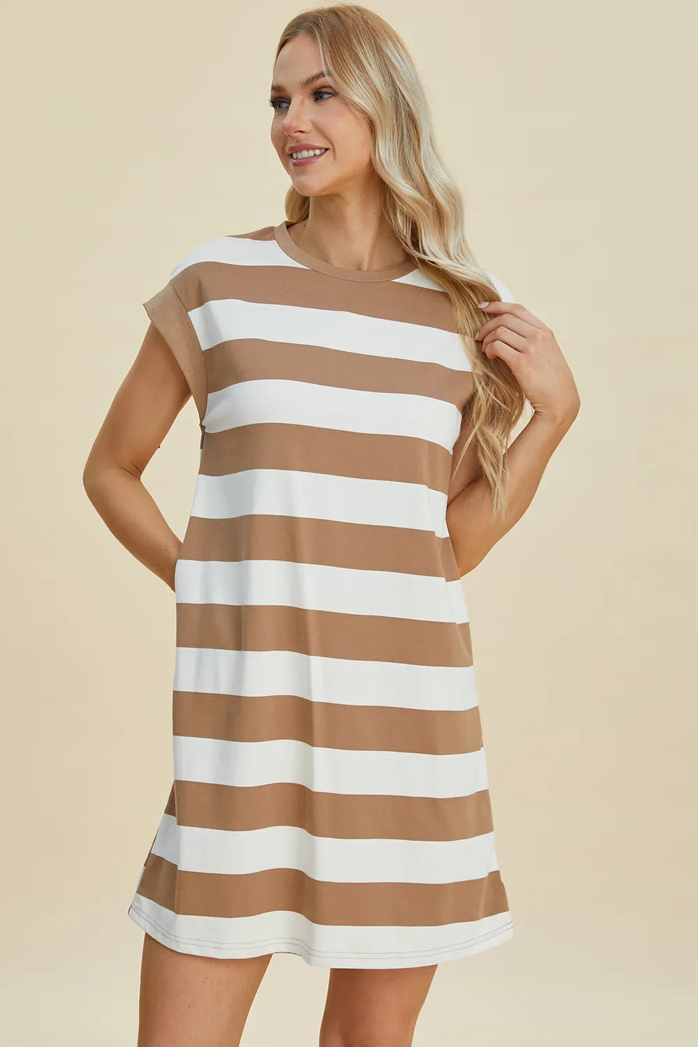 Woman wearing a brown and white striped dress against a beige background