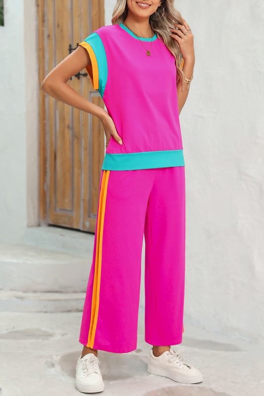 Woman wearing a bright pink outfit with colorful accents standing on a white background