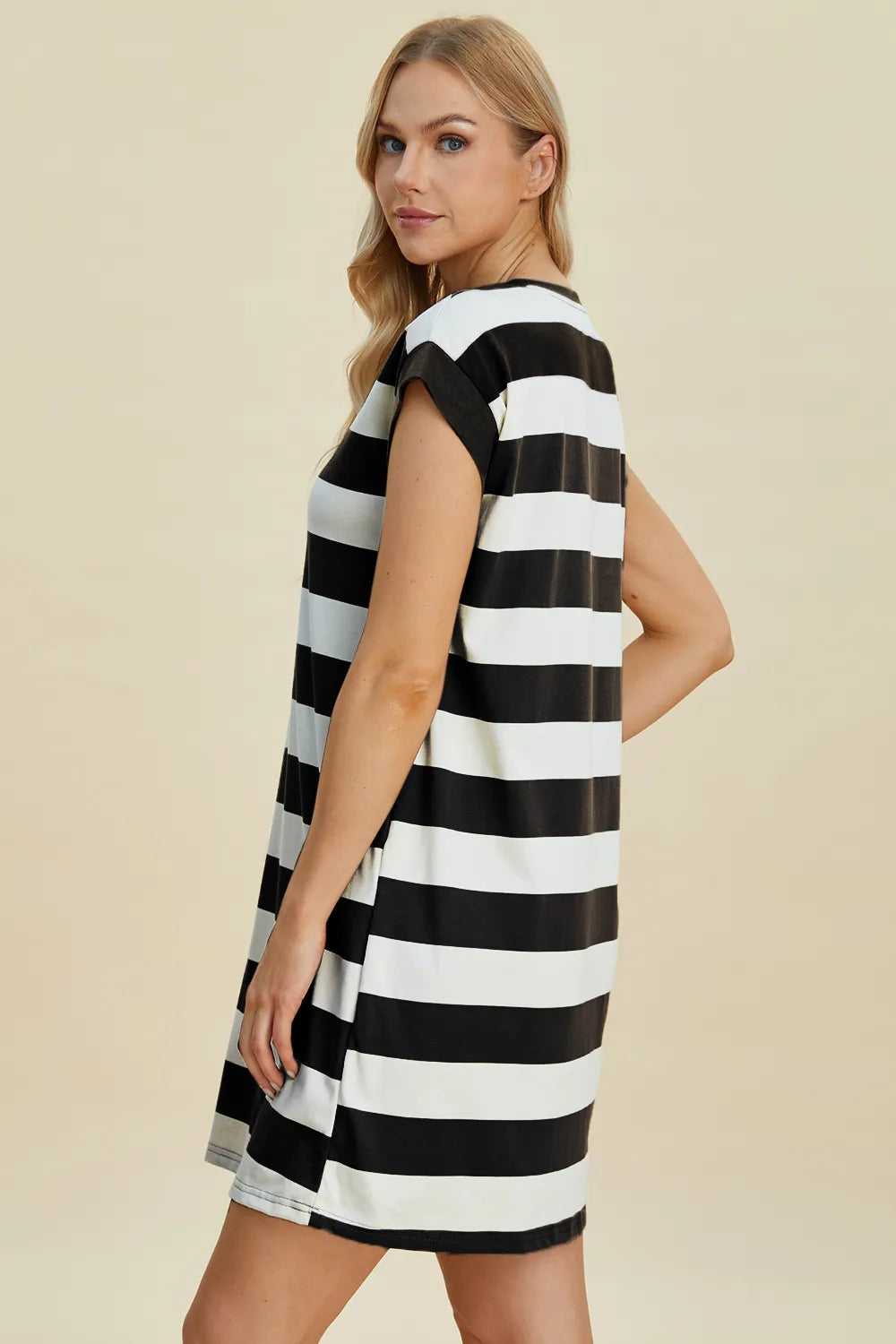 Woman wearing a black and white striped dress against a beige background