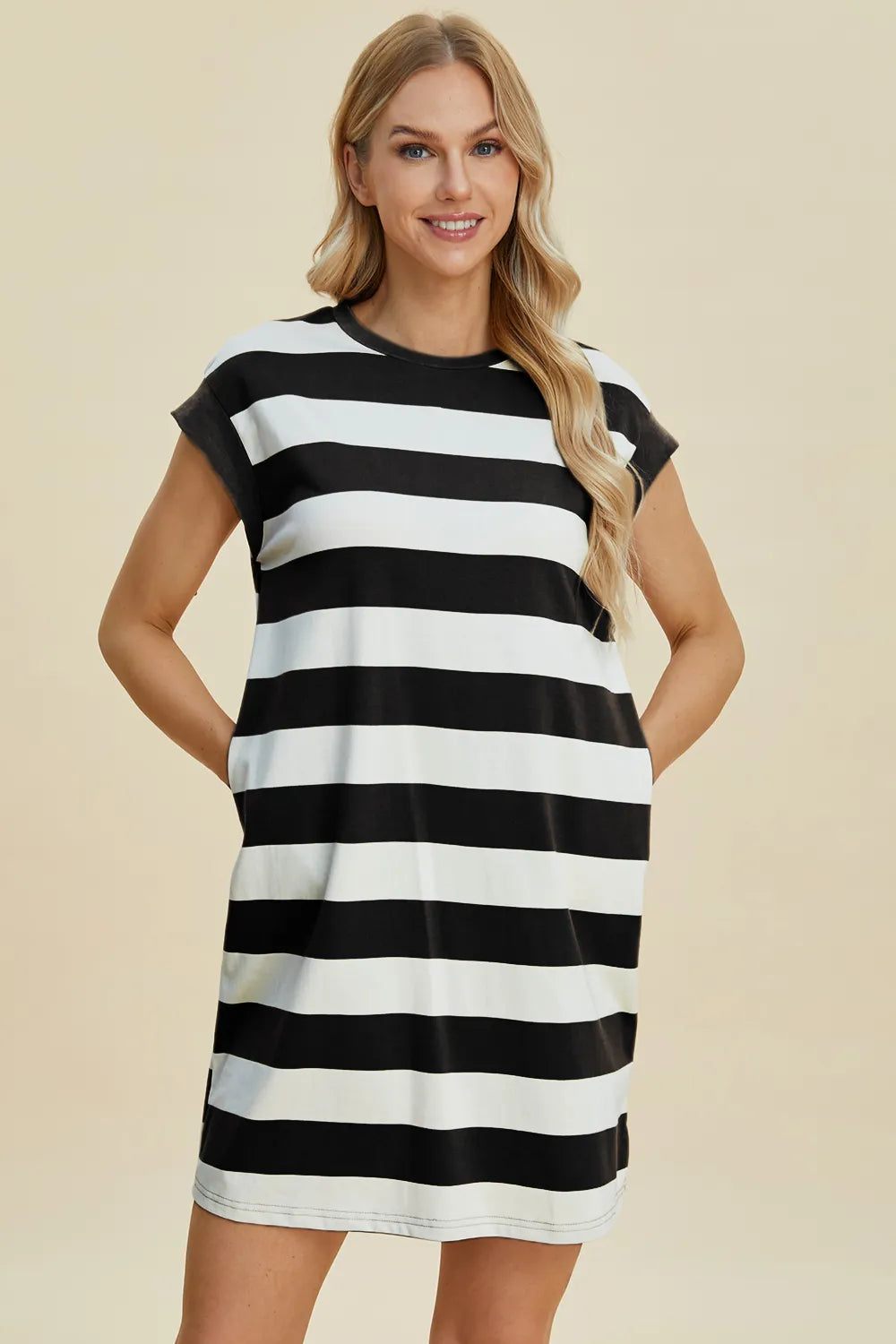 Woman wearing a black and white striped dress on a beige background