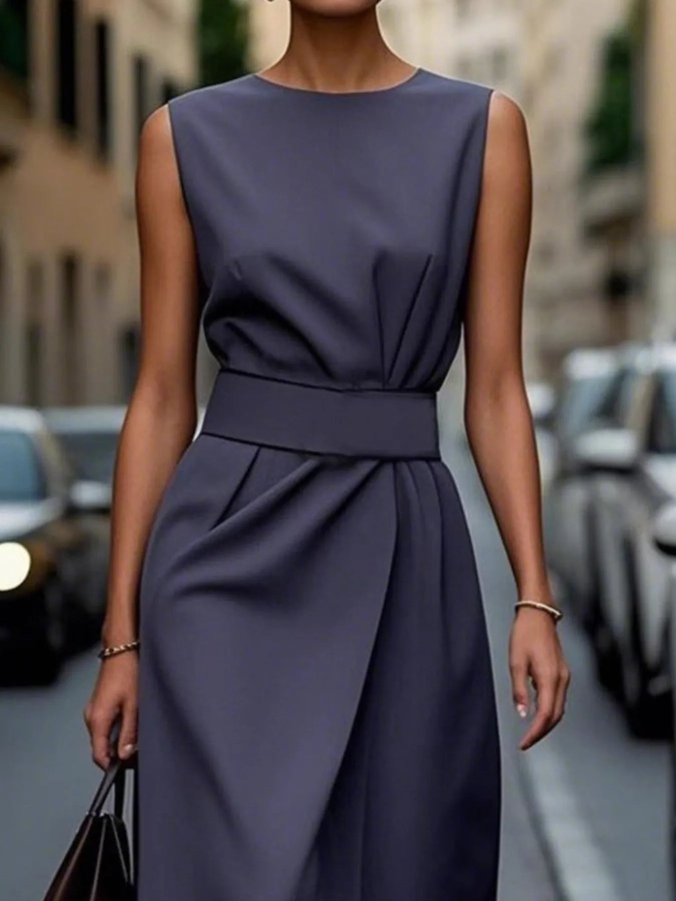 Woman wearing a sleeveless navy dress on a city street.