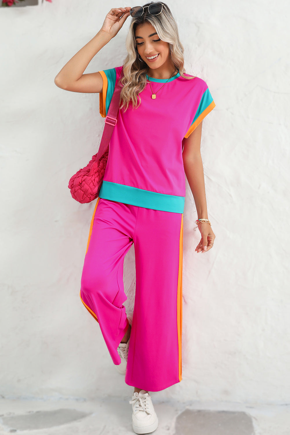 Woman wearing a bright pink outfit with colorful accents against a white background