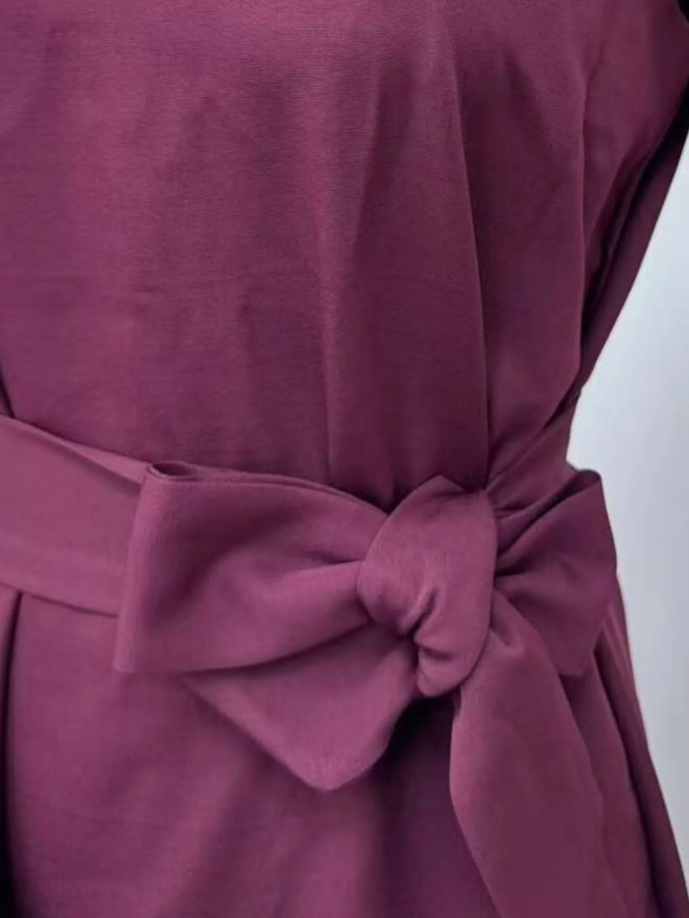 Close-up of a purple dress with a bow detail on a white background
