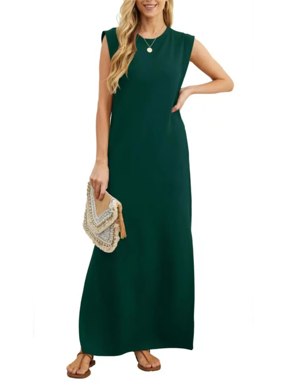 Woman wearing a green sleeveless dress holding a beaded handbag on a white background