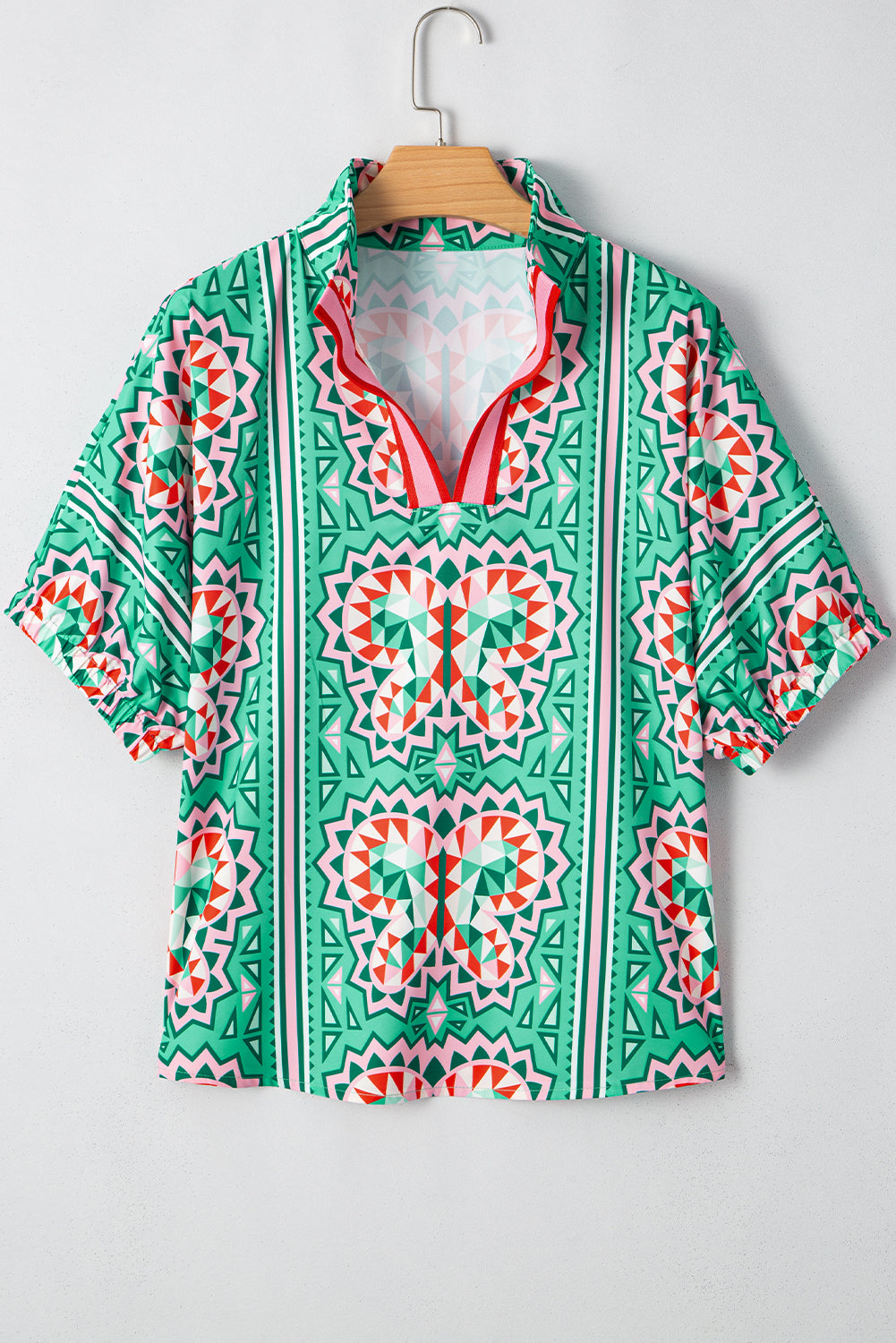 Green and pink patterned shirt on a hanger against a white background
