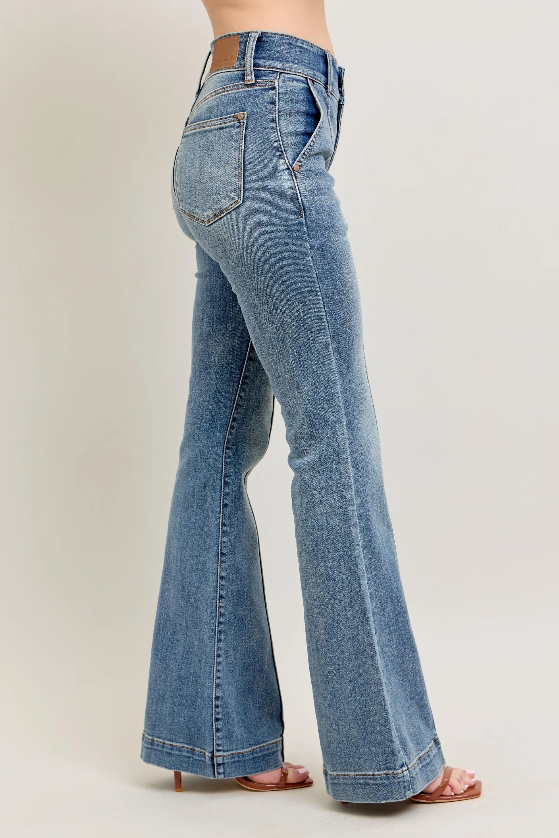 Blue jeans worn by a person on a plain background