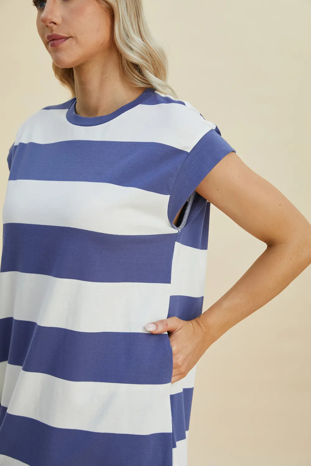 Woman wearing a blue and white striped dress against a beige background