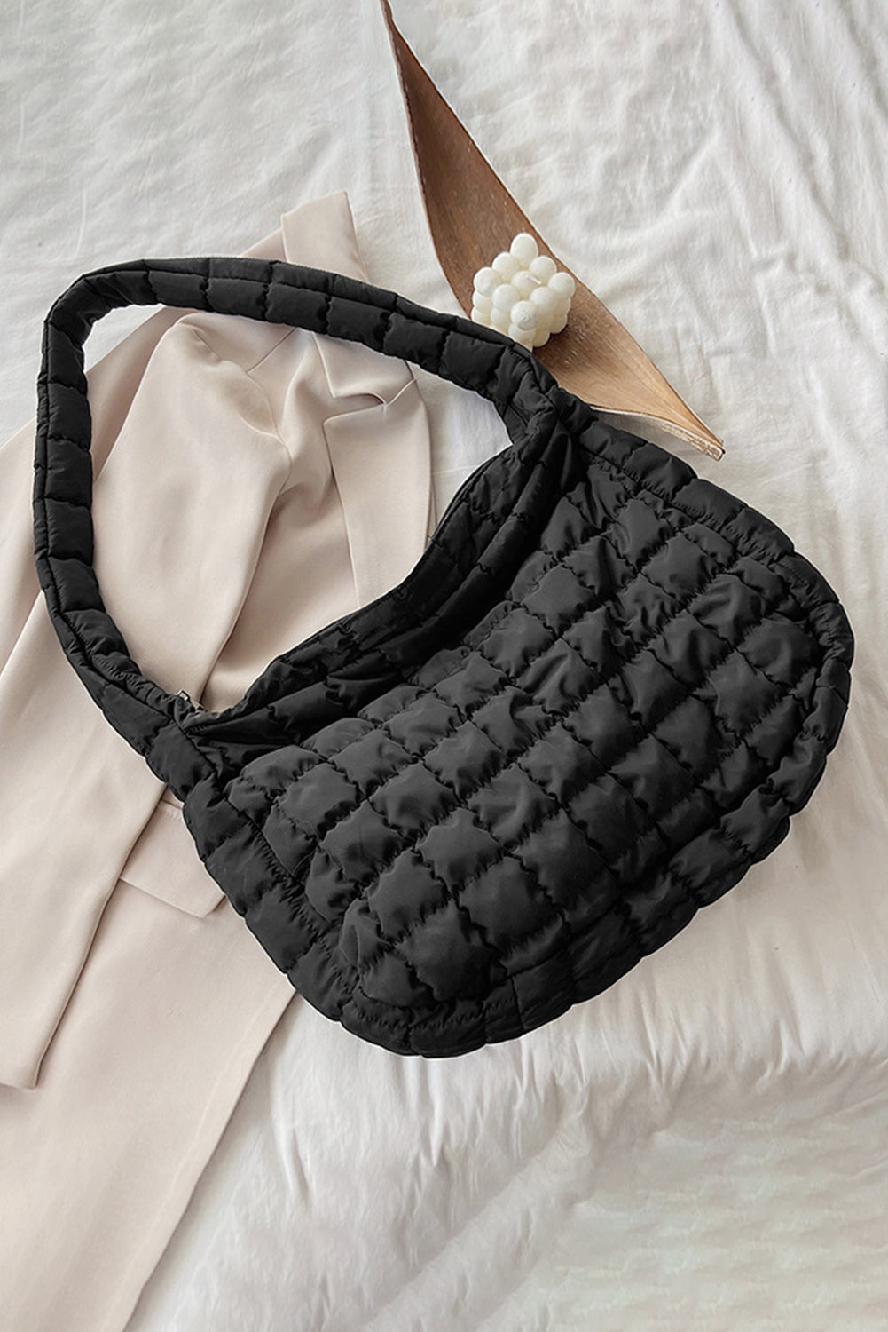Black quilted fanny pack on a light beige fabric background