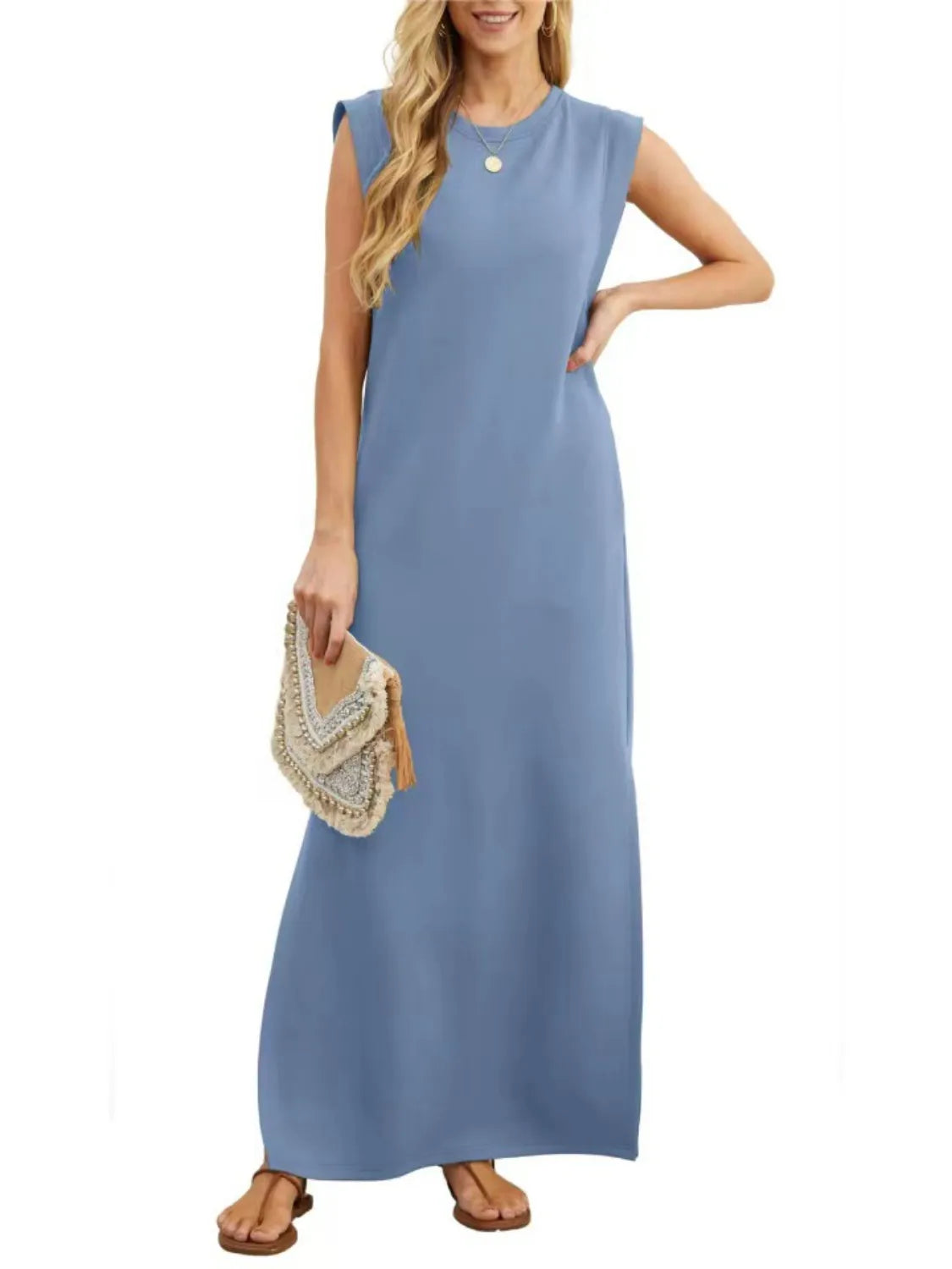Woman wearing a blue sleeveless dress holding a beige clutch on a white background