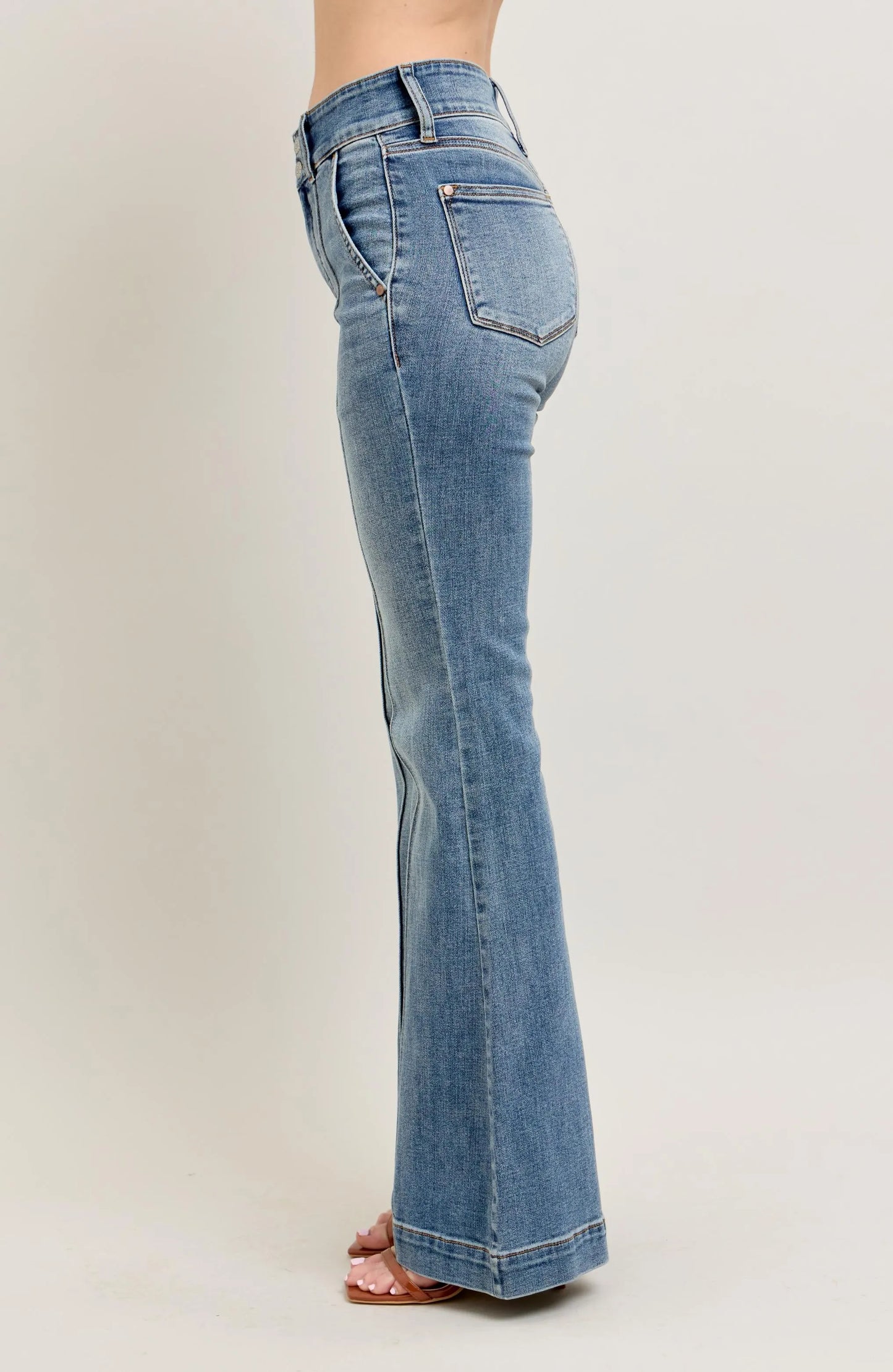 Blue jeans worn by a person on a plain background