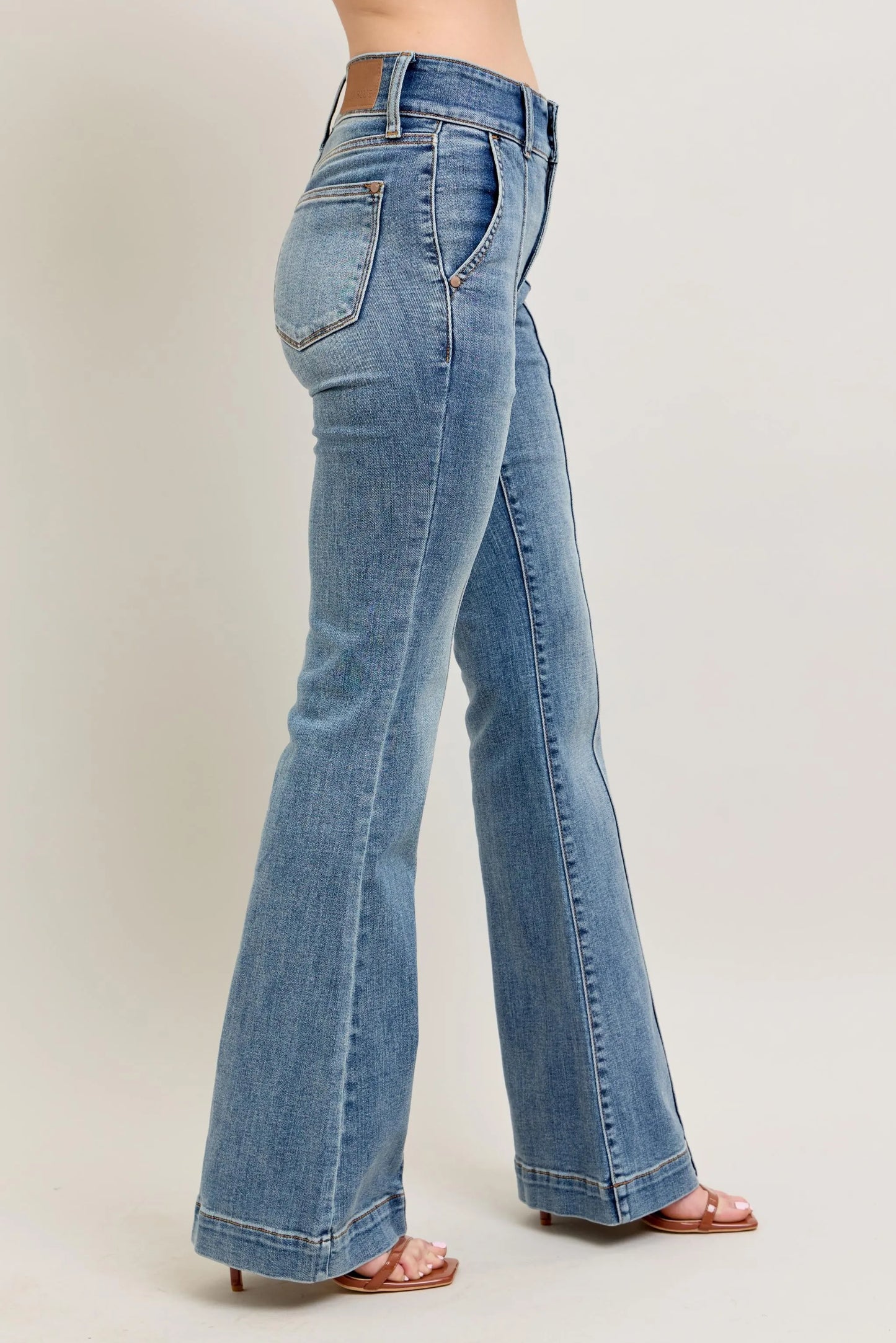 Blue jeans worn by a person on a plain background