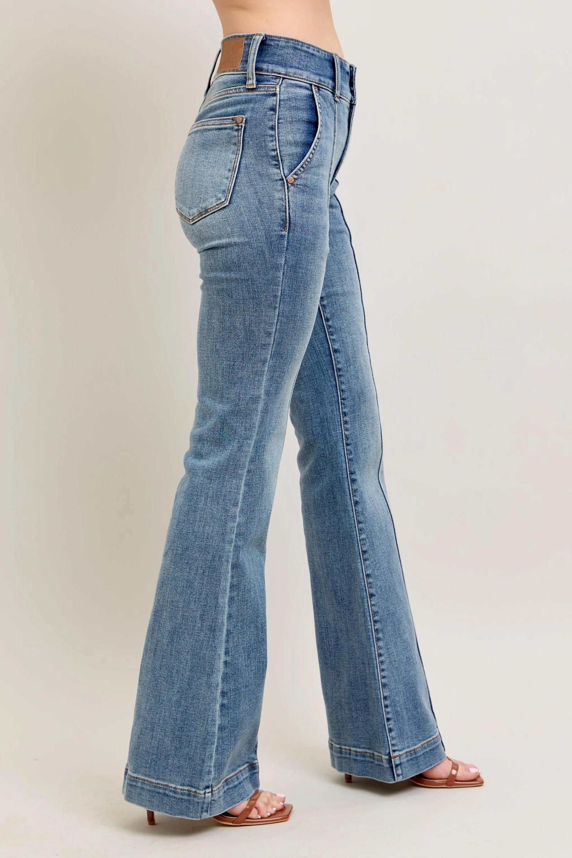Blue jeans worn by a person on a plain background