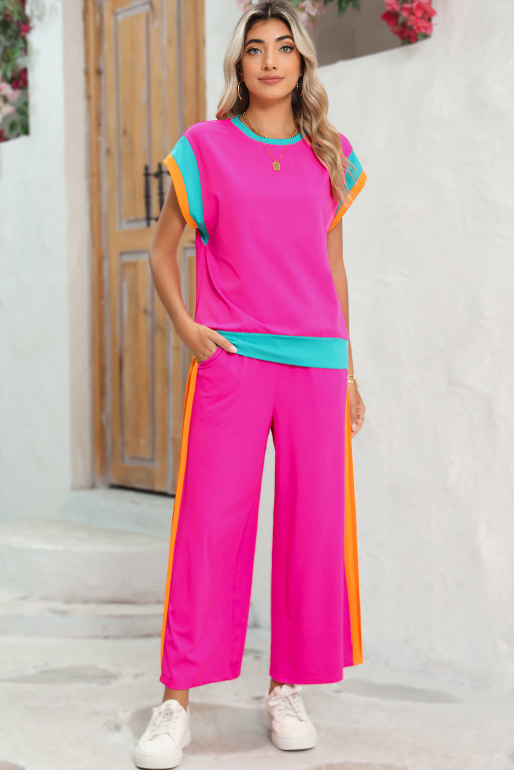 Woman wearing a colorful outfit with a pink top and wide-leg pants in an outdoor setting.