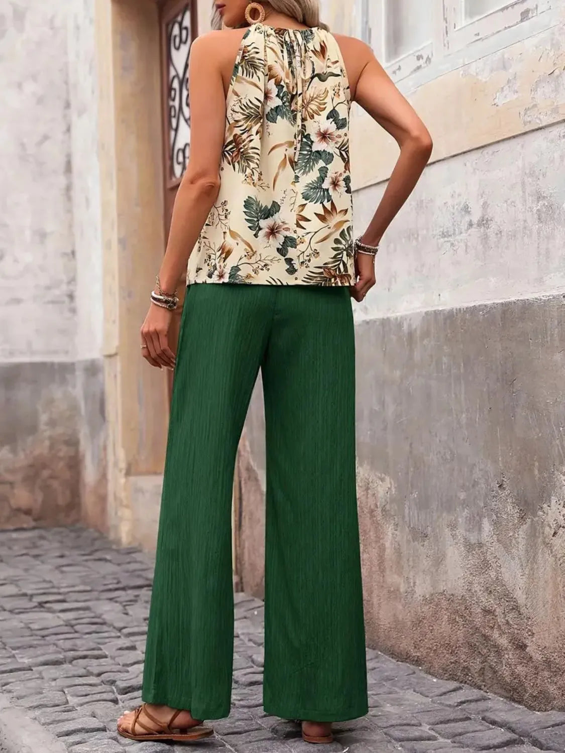 Person wearing a floral top and green pants on a stone pavement.