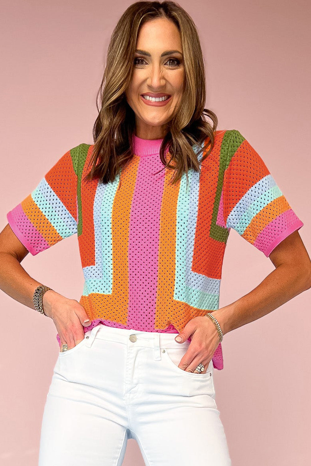 Woman wearing a colorful striped sweater against a pink background