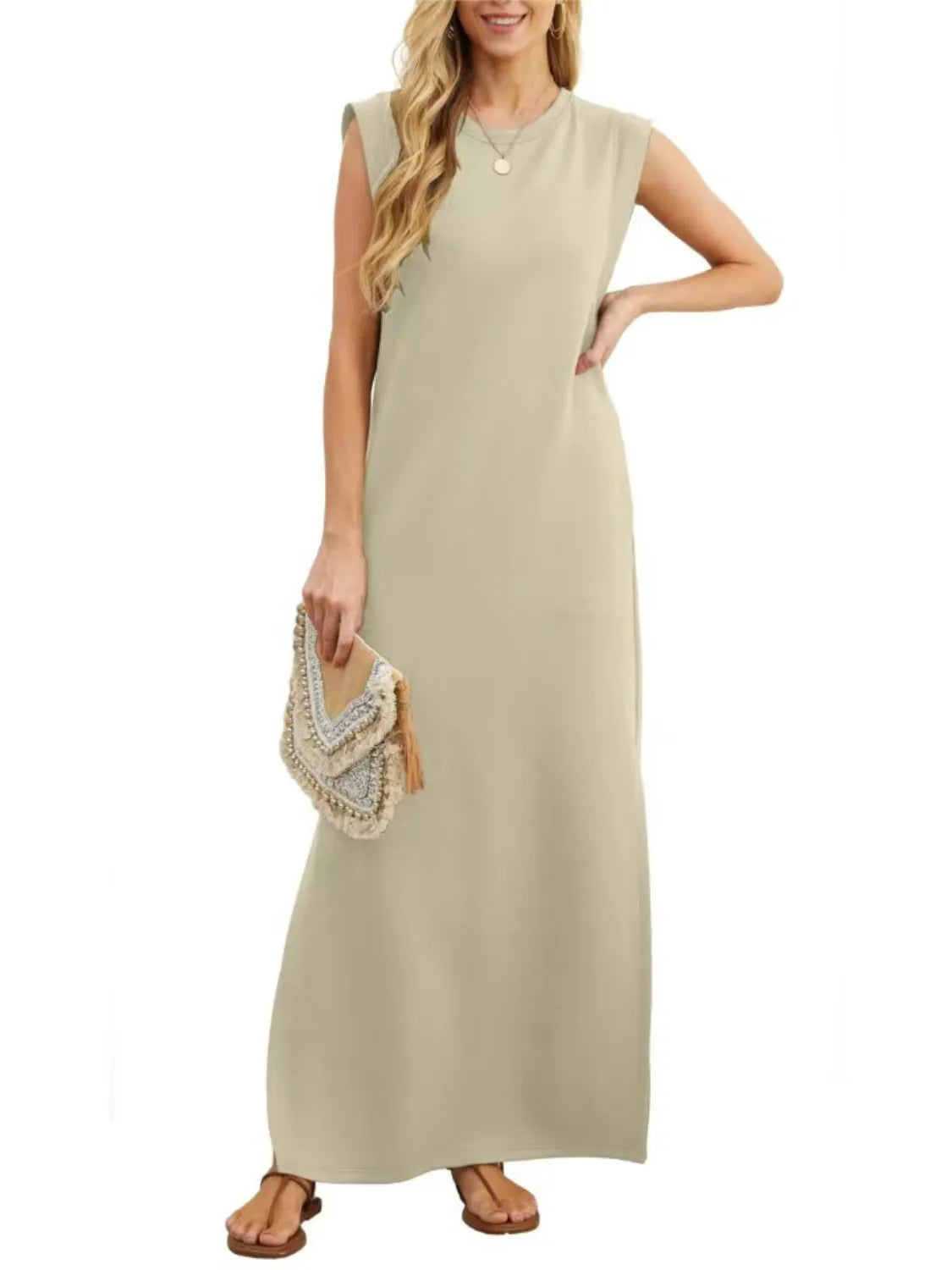 Woman wearing a beige sleeveless dress holding a clutch on a white background