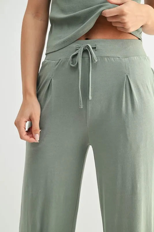 Person wearing green lounge pants and a matching top on a white background